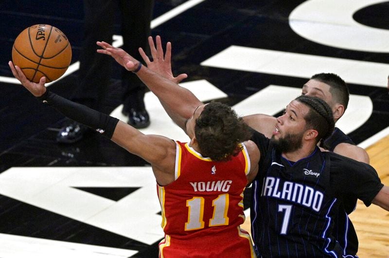 Hawks guard Trae Young (11) is fouled by Magic guard Michael Carter-Williams (7) while going for a shot near the end of the second half Wednesday, March 3, 2021, in Orlando, Fla. (Phelan M. Ebenhack/AP)