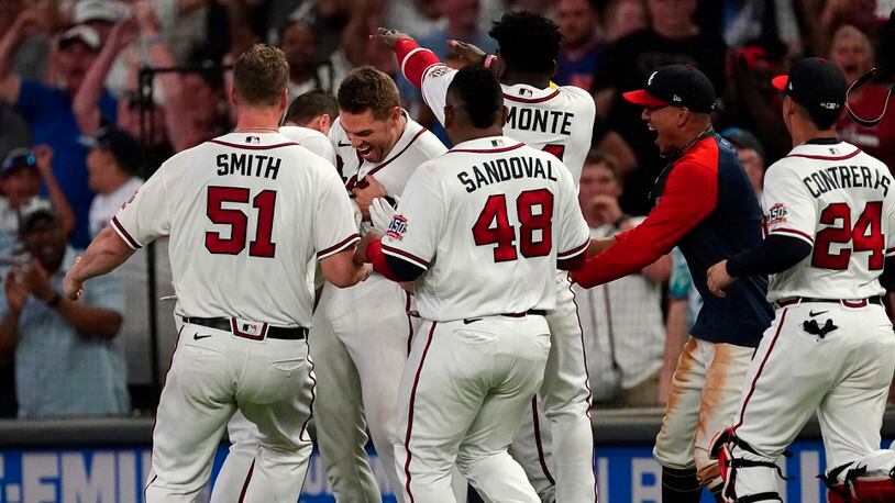 Freddie Freeman is mobbed by his teammates after driving in the game-winning run with an infield base hit in the ninth inning of a baseball game against the New York Mets on Thursday, July 1, 2021, in Atlanta.