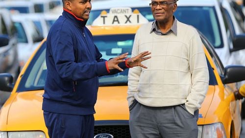 Claude Mayfield (right), 75, who has been a cab driver for more than 30 years at Hartsfield-Jackson International, chats with driver Sharmarke Yonis in the cab holding area. Cab services say they're being hurt by new arrivals such as ride-sharing service Uber and national chain SuperShuttle.
