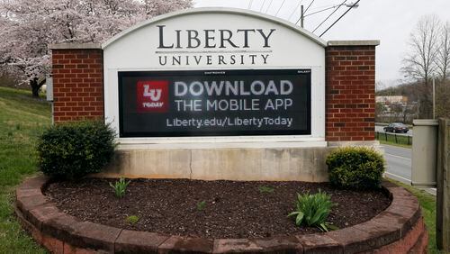 FILE - In this March 24 , 2020, file photo, a sign marks the entrance to Liberty University in Lynchburg, Va. The university, led by Jerry Falwell Jr., is pushing for criminal trespassing charges to be lodged against two journalists who pursued stories about why the evangelical college has remained partially open during the coronavirus outbreak. (AP Photo/Steve Helber, File)