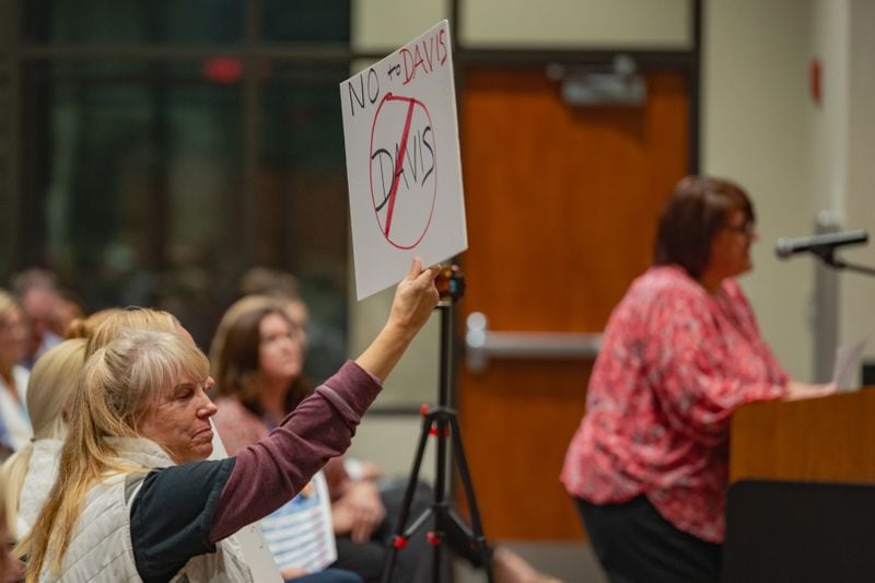 A parent holds up a sign expressing her opposition to the Cherokee County school board hiring Mary Elizabeth Davis as its next superintendent election during a school board meeting on Thursday, February 15, 2024, in Canton, Georgia, at Cherokee's Frank R. Petruzielo Educational Services Facility. (Atlanta Journal-Constitution/Jason Allen)