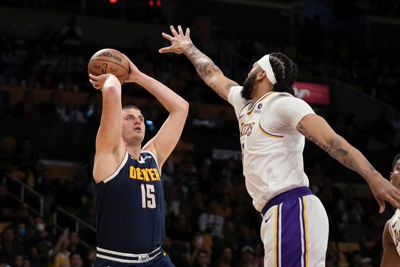 Denver Nuggets center Nikola Jokic, left, shoots as Los Angeles Lakers forward Anthony Davis defends during the first half in Game 4 of an NBA basketball first-round playoff series Saturday, April 27, 2024, in Los Angeles. (AP Photo/Mark J. Terrill)