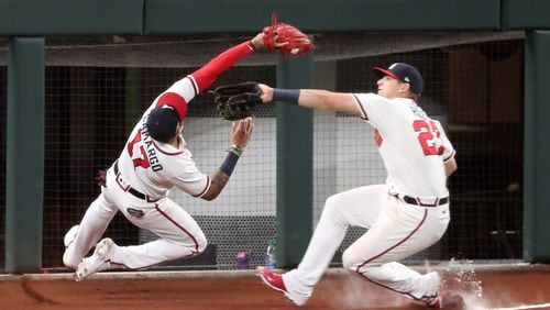Johan Camargo, playing third base, makes a catch and almost collides with Austin Riley, playing left field, in Game 3 of the National League Championship Series on Wednesday at Globe Life Field in Arlington, Texas. (Curtis Compton / Curtis.Compton@ajc.com)