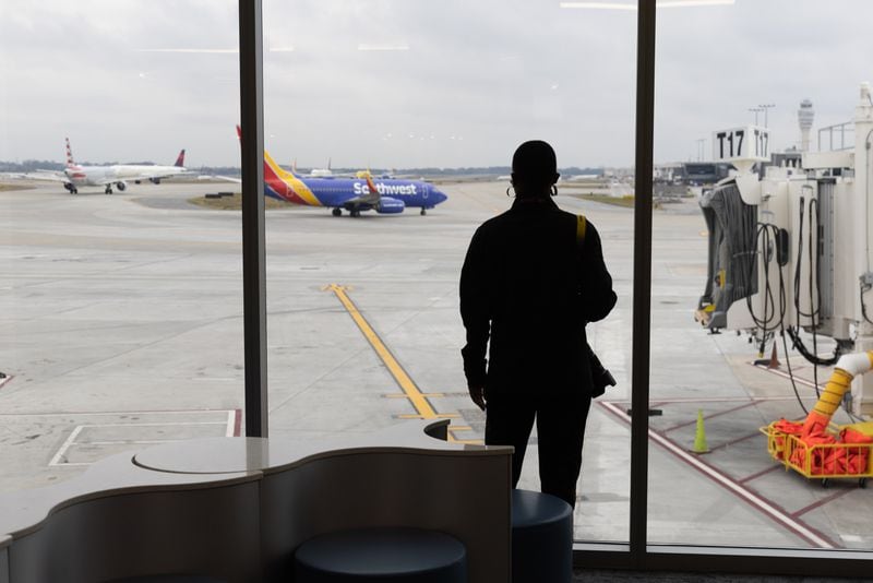 Travelers watch jets depart in the new Concourse T extension at Hartsfield-Jackson Atlanta International Airport Tuesday, December 13, 2022.    (Steve Schaefer/steve.schaefer@ajc.com)