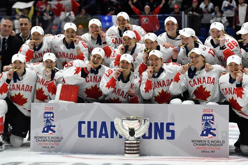 Team Canada players pose with their gold medals and the championship cup after beating the United States in the final at the IIHF Women's World Hockey Championships in Utica, N.Y., Sunday, April 14, 2024. (AP Photo/Adrian Kraus)