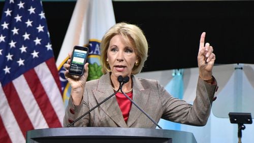 U.S. Education Secretary Betsy DeVos shows FAFSA mobile app as she speaks during 2018 FSA Training Conference at Georgia World Congress Center in Atlanta in November 2018. DeVos announced Wednesday her department is temporarily suspending loan collections for default borrowers. HYOSUB SHIN / HSHIN@AJC.COM
