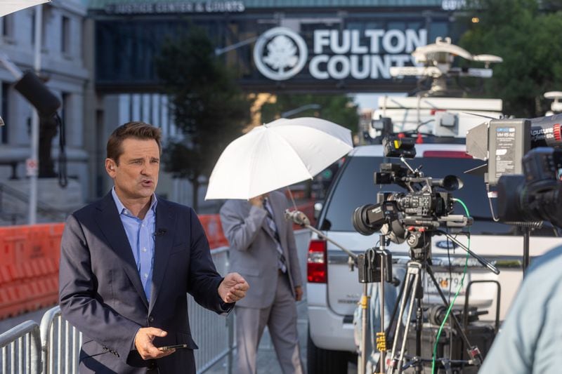 John Huddy with Newsmax reports outside of the Fulton County Courthouse on Tuesday, the day after a grand jury indicted former President Donald Trump and 18 others in an election interference case.