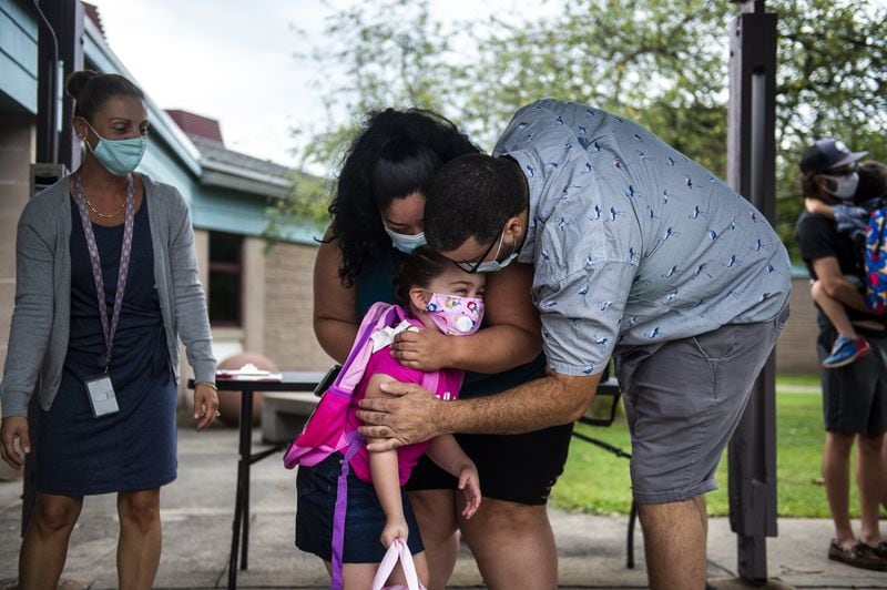 Madisyn Sweeney, 5, is hugged by her parents Rebecca Cedeno and Randall Sweeney, during the first day back to school at Lawrence Elementary School Thursday, Sept. 3, 2020, in Middletown.