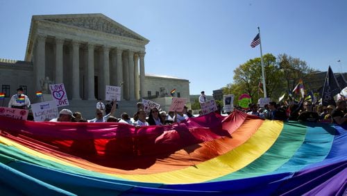In this April 28, 2015 file photo, demonstrators stand in front of a rainbow flag of the Supreme Court in Washington. (AP Photo/Jose Luis Magana, File)