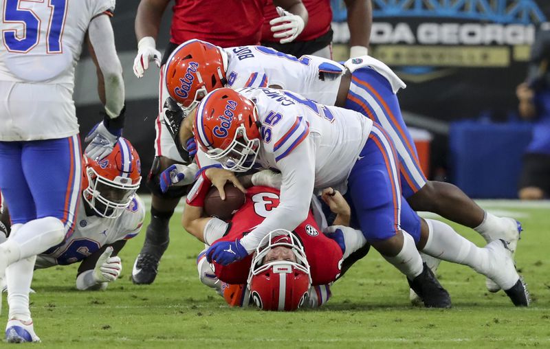 Georgia quarterback Stetson Bennett (13) is taken down at the line of scrimmage by Gators defensive lineman Kyree Campbell (55) in the first half Saturday, Nov. 11, 2020, in Jacksonville, Fla.