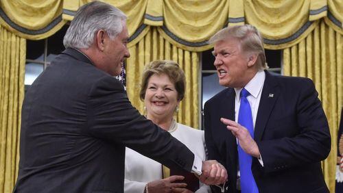 President Donald Trump (R) shakes hands with Rex Tillerson (L) as Tillerson's wife Renda St. Clair look on after Tillerson was sworn in as Secretary of State in the Oval Office at the White House in Washington, DC, on February 1, 2017.