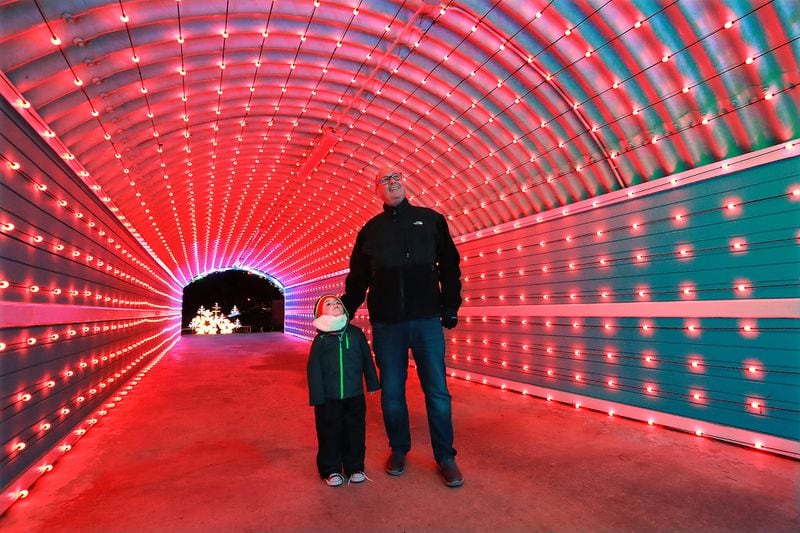 Ralph Thomas and his 4-year-old grandson Logan Thomas make their way through a new tunnel of lights in Margaritaville at Lanier Islands in Buford. Curtis Compton/ccompton@ajc.com