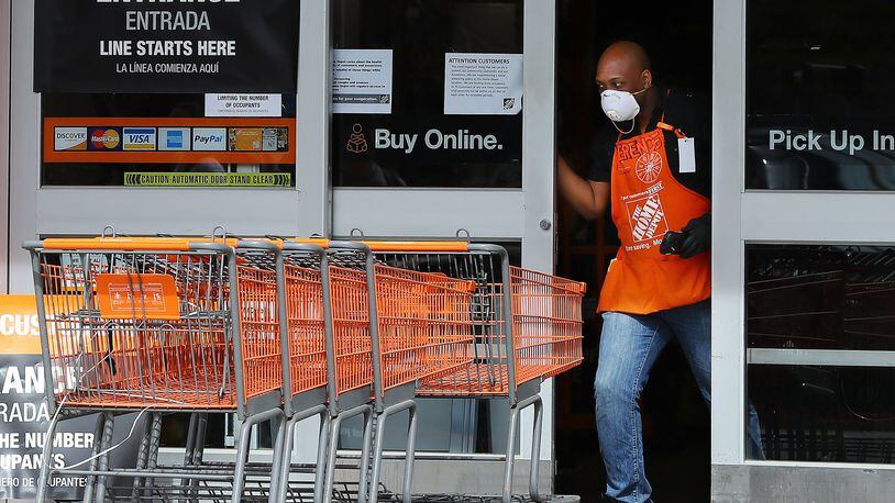 A Home Depot employee opens the doors to the store at Midtown Place to let the next few customers in while the store limits the number of occupants to maintain six feet of space between shoppers and help prevent the spread of coronavirus on March 29, 2020, in Atlanta. Curtis Compton ccompton@ajc.com