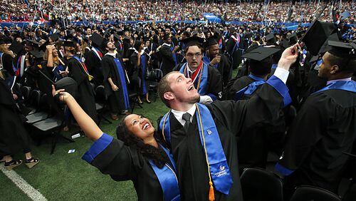 Georgia State University undergraduates Stephanie-Joy Rhoden, of Miami, Fla., left, and her fiance Jon-Michael Drain, of Douglasville, celebrate at the conclusion of the Spring 2014 Commencement at the Georgia Dome Saturday afternoon, May 10, 2014. Rhoden and Drain, both journalism majors met while at GSU.
