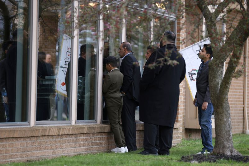People peek in the windows outside the Islamic Institute of America in Dearborn Heights, Mich., hoping to see Iraq's Prime Minister Mohammed Shia al-Sudani, Thursday, April 18, 2024. (AP Photo/Al Goldis)