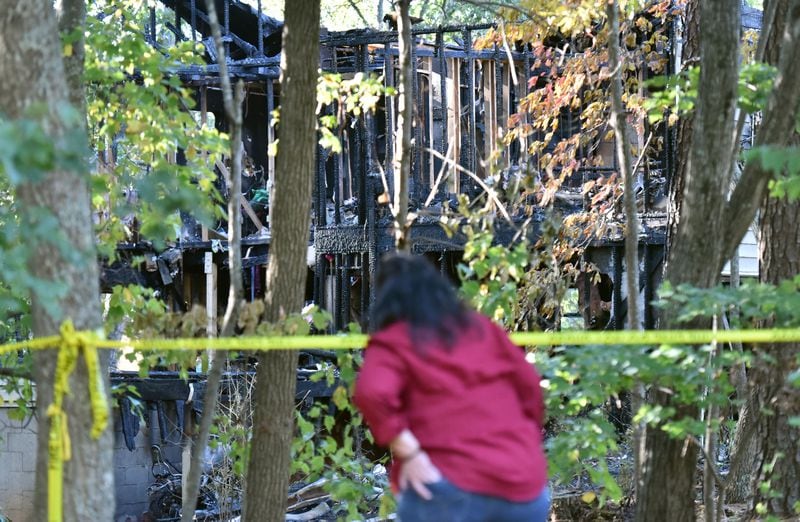 A neighbor checks out the house where five adults were found dead after a fire gutted the home in unincorporated Dulut near Old Peachtree Road. HYOSUB SHIN / HSHIN@AJC.COM