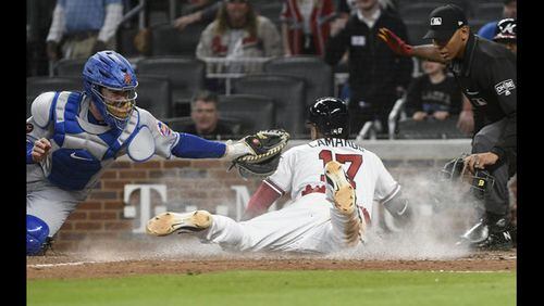The Braves’ Johan Camargo slides across the plate with the winning run on Ender Inciarte’s walk-off bunt single in the ninth inning Saturday. (AP Photo/John Amis)