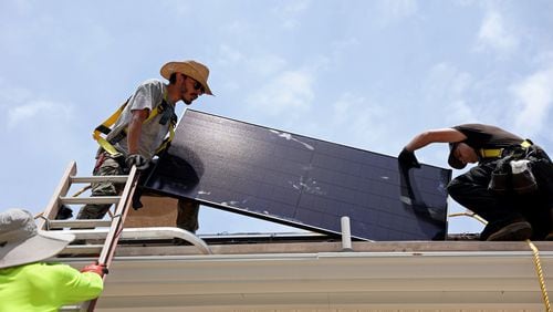 Alternative Energy Southeast employees Aaron Basto, center, and Russell McCune, right, installs one of eighteen solar panels to the roof of a resident Tuesday, June 7, 2022, in Ellenwood, Ga. (Jason Getz / Jason.Getz@ajc.com)
