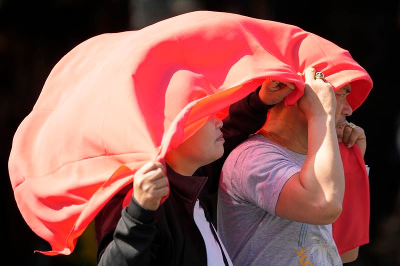 FILE - A man and woman use a cloth over their heads to protect themselves from the sun in Manila, Philippines on April 29, 2024. In a world growing increasingly accustomed to wild weather swings, the last few days and weeks have seemingly taken those environmental extremes to a new level. (AP Photo/Aaron Favila, File)