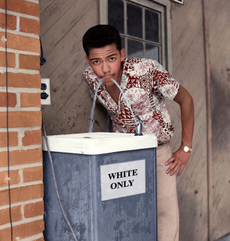 A colorized version of Cecil Williams taking a drink out of a white's only water fountain.