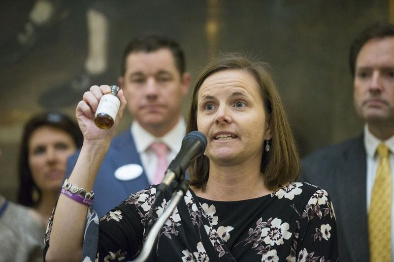 Shannon Cloud, a parent of a child who suffers from seizures, holds up a bottle of THC oil during a press conference in the rotunda of the Georgia State Capitol building in Atlanta in February. Cloud was surrounded by other families and lawmakers on Thursday as they proposed a law that would grant the legalization of growing and distributing medical marijuana to registered patients (ALYSSA POINTER/ALYSSA.POINTER@AJC.COM)