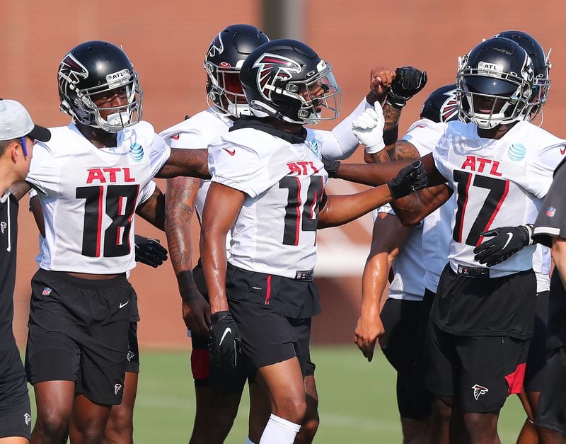 The Falcons' wide receivers group, including Calvin Ridley (from left), Russell Gage and Olamide Zaccheaus give each other a fist bump as they take the field for the first day of practice during training camp Thursday, July 29, 2021, at the team's training facility in Flowery Branch. (Curtis Compton / Curtis.Compton@ajc.com)
