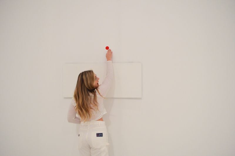 SCAD student Madilyn Bedsole puts the first sticker in the “Obliteration Room.” CONTRIBUTED: HIGH MUSEUM OF ART
