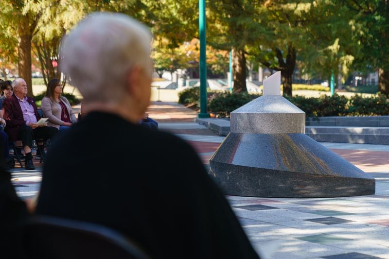 A new monument installed on the Quilt of Remembrance aimed in the direction of the bomb blast is seen behind Bobi Jewell, mother of Richard Jewell, as she listens to a speaker during a dedication ceremony honoring Mr. Jewell and first responders at Centennial Olympic Park, on Wednesday, November 10, 2021, in Atlanta. (Elijah Nouvelage for The Atlanta Journal-Constitution)