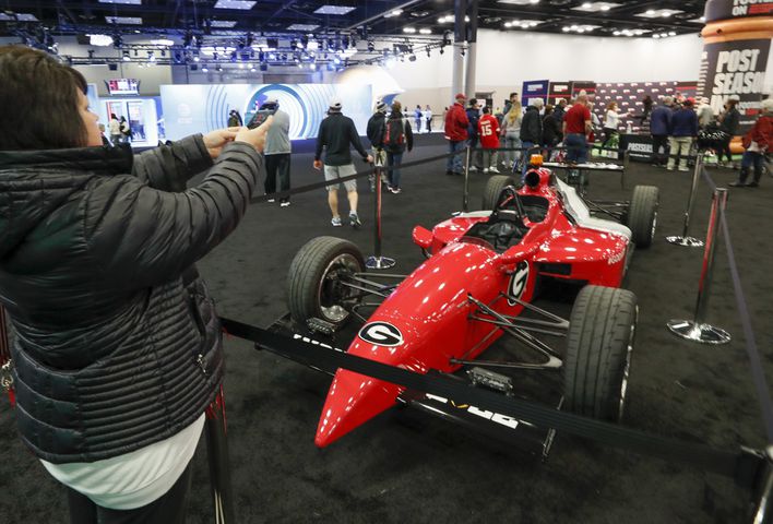 Felicia Stephens, from Dawsonvile, makes a photo of the Georgia-themed Indy car at Fan Central in the Indiana Convention Center at the 2022 College Football Playoff National Championship  between the Georgia Bulldogs and the Alabama Crimson Tide at Lucas Oil Stadium in Indianapolis on Saturday, January 8, 2022.   Bob Andres / robert.andres@ajc.com