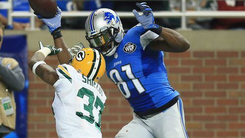 Before taking early retirement, Detroit's Calvin Johnson towers over and toys with a Green Bay defender. (Andrew Weber/Getty Images)