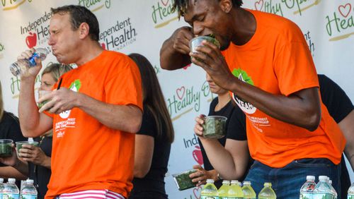 Two-time kale eating champion Gideon Oji, right, downs a container of the leafy green vegetable, while hot-dog-eating champ Joey Chestnut, left, takes a drink of water during Sunday's Kale Yeah! Competition at the Erie County Fair in Hamburg, N.Y.