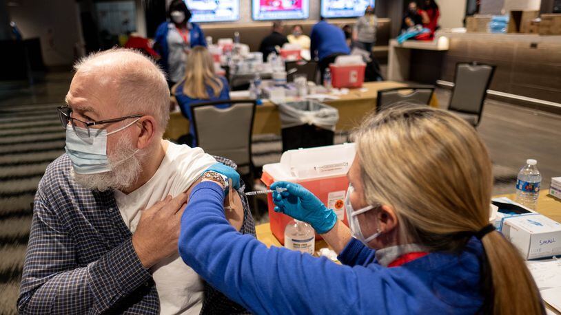 210116-Atlanta- Ronald Murphey looks away as he gets his  COVID-19 vaccine during an event Saturday morning, Jan. 16, 2021, for Fulton County School employees and their spouses who are 65 and older at Mercedes-Benz Stadium. (Photo: Ben Gray for The Atlanta Journal-Constitution)