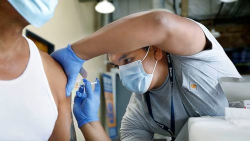 In this file photo, Jeremy Oyague, right, a registered nurse with The Los Angeles Department of Public Health, administers a COVID booster at a vaccination clinic to immunize people against monkeypox and COVID at The Village Mental Health Services in Los Angeles, a site run by The People Concern. (Christina House/Los Angeles Times/TNS)