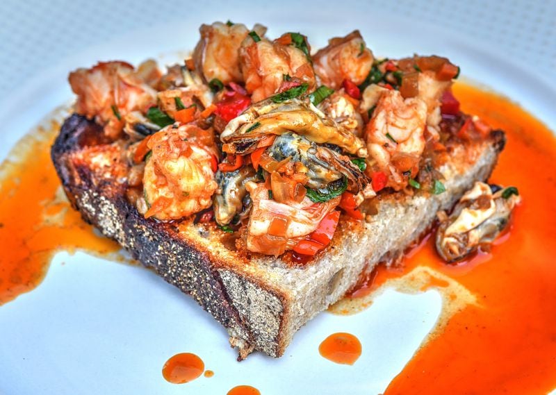 Shellfish Escabeche, a mixture of cooked shellfish in a rich sauce, is served here on bread. (Food styling by Brian Wolfe and Bryan Rackley / Chris Hunt for The AJC)