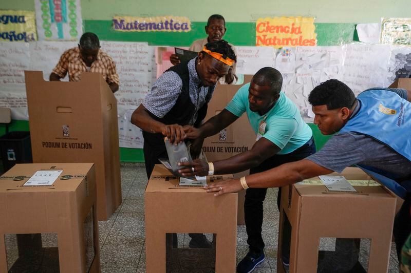 Electoral officials assist a voter to cast his ballot during general elections in Santo Domingo, Dominican Republic, Sunday, May 19, 2024. (AP Photo/Matias Delacroix)