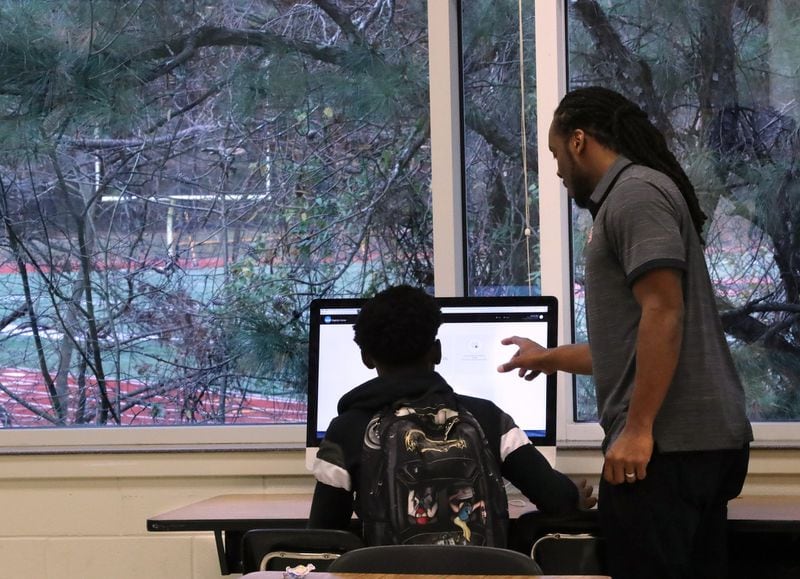 Play It Smart academic coach Matthew Hazel helps safety Keshaun Ward review information in the online NCAA Clearinghouse after school in his classroom overlooking the practice football field at Therrell High School on Monday, Dec. 16, 2019, in Atlanta. CURTIS COMPTON/CCOMPTON@AJC.COM