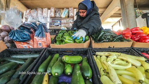 Dominos Roci endures the cold on Monday morning to set up a vegetable stand at the Atlanta State Farmers Market in Forest Park.