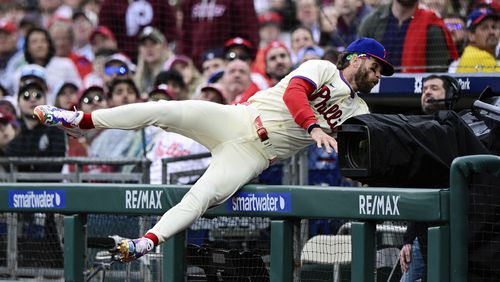 Philadelphia Phillies' Bryce Harper falls into the dugout as he gives chase for a foul ball during the first inning of a baseball game against the Atlanta Braves, Saturday, March 30, 2024, in Philadelphia. (AP Photo/Derik Hamilton)