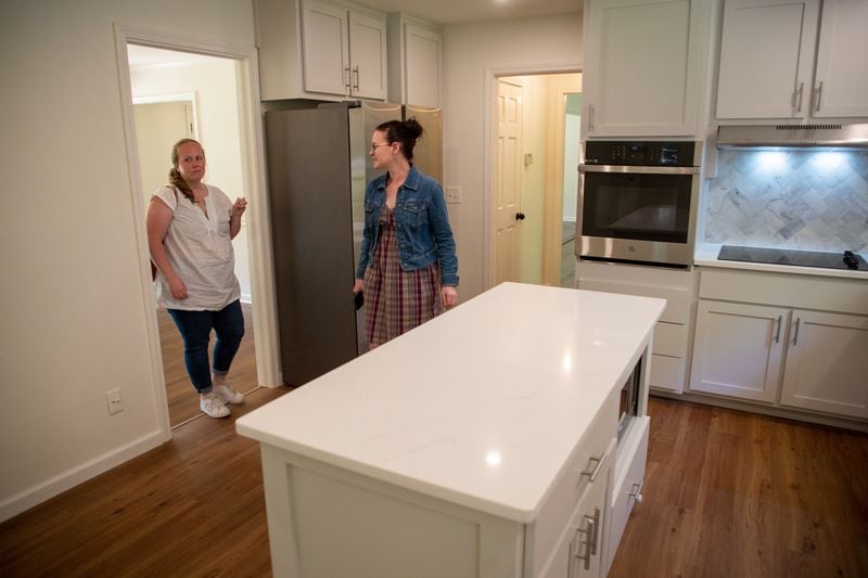 Real Estate agent Maura Neill, right, looks over a kitchen of a Roswell house that is for sale with homebuyer Anna Devlin on Friday, April 29, 2022. (Steve Schaefer / Steve. Schaefer@ajc.com)