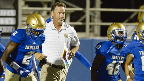 McEachern head coach Kyle Hockman (center) takes the field along with the Indians prior to the start of their game against Cedar Grove Friday, Sept. 7, 2018, at McEachern High School in Powder Springs.