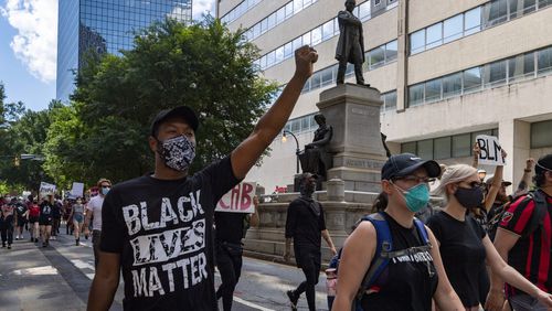 Protesters walk down Marietta Street on June 13, 2020, past a statue of orator and journalist Henry Grady, during a rally over police shootings. There are increasing calls to erase Grady's name from buildings, including Grady High School.   JOHN AMIS FOR THE ATLANTA JOURNAL-CONSTITUTION.