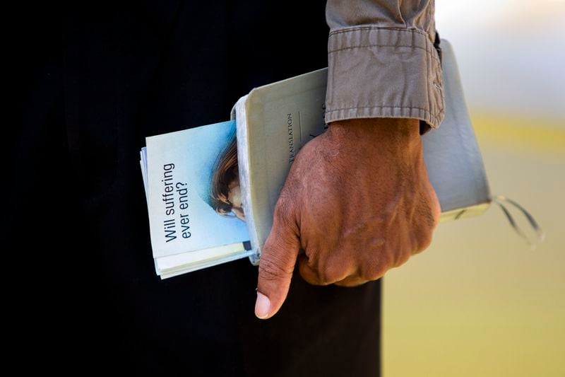Sam Hall, a Jehovah's Witness, goes door-to-door, bible in hand, on Thursday, September 15, 2022, in Atlanta.  The group resumed their door-to-door ministry after pausing for two-and-a-half-years due to the coronavirus pandemic. CHRISTINA MATACOTTA FOR THE ATLANTA JOURNAL-CONSTITUTION.