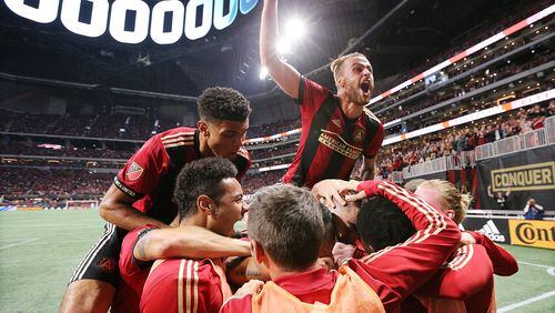 Atlanta United midfielder Miguel Almiron is covered up by teammates after scoring his team’s second goal of the night on a penalty kick for a 2-0 lead over New York City during the first half in their MLS Eastern Conference Semifinal playoff match on Sunday, Nov. 11, 2018, in Atlanta.  Curtis Compton/ccompton@ajc.com