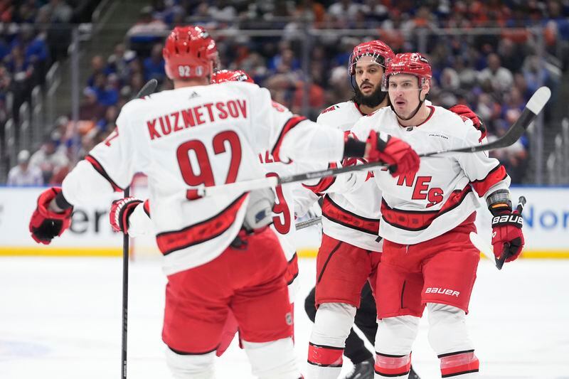 Carolina Hurricanes' Dmitry Orlov, right, celebrates with Jalen Chatfield, second from left and Evgeny Kuznetsov (92) after scoring a goal against the New York Islanders during the first period of Game 3 of an NHL hockey Stanley Cup first-round playoff series Thursday, April 25, 2024, in Elmont, N.Y. (AP Photo/Frank Franklin II)
