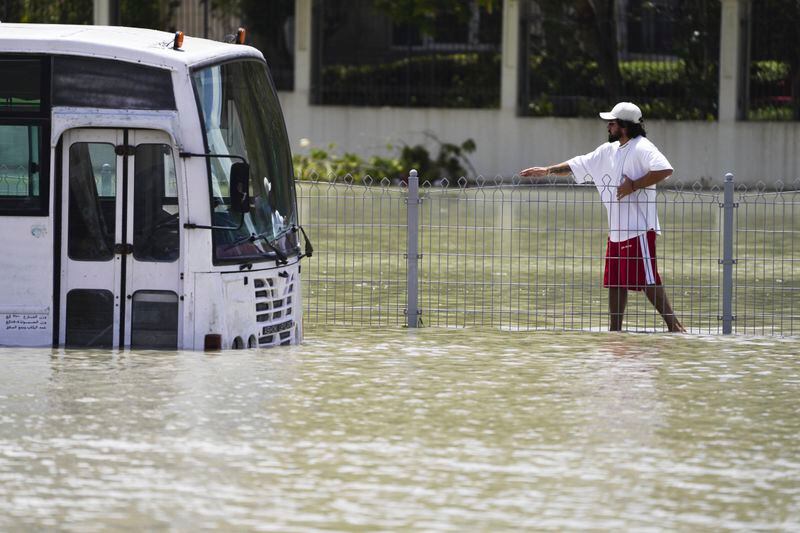 A man walks through floodwater in Dubai, United Arab Emirates, Wednesday, April 17, 2024. The desert nation of the United Arab Emirates attempted to dry out Wednesday from the heaviest rain ever recorded there after a deluge flooded out Dubai International Airport, disrupting the world's busiest airfield for international travel. (AP Photo/Jon Gambrell)