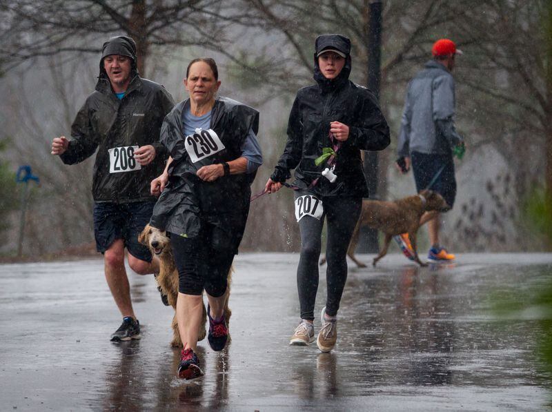 Runners and their dogs aren’t deterred by heavy rain on their way to the finish line during the Piedmont Park Conservancy's 5th Year Anniversary of the Doggie Dash in Piedmont Park on Sunday, March  11, 2018.  STEVE SCHAEFER / SPECIAL TO THE AJC