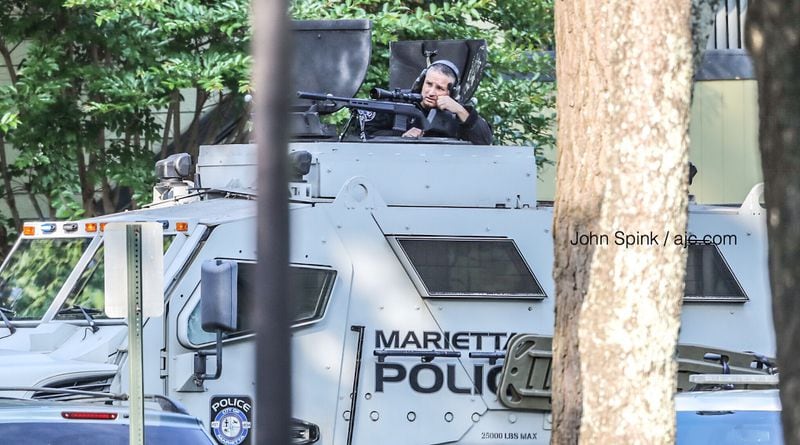 A sniper sits ready in a Marietta police SWAT vehicle Thursday morning at The Park on Windy Hill apartments, where an aggravated battery suspect is hiding out inside an attic. 