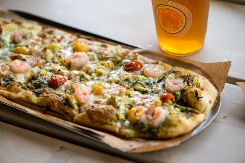 Slim and Husky's California Love pizza with spinach basil pesto, house cheese blend, artichoke, sliced tomato blend, red onion, and shrimp. Photo credit- Mia Yakel.