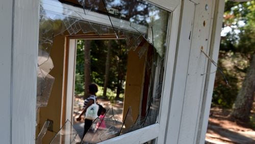 September 7, 2016 Decatur, GA: A woman and small cild walk past the shattered window of the guard shack at Creekside Forest Apartment Homes in Decatur. The complex has fallen into disrepair. The few residents who remain are living rent free but with no maintenance services or support. The leasing office has been closed for several months, mail is no longer delivered, windows are broken, and litter covers the ground. BRANT SANDERLIN/BSANDERLIN@AJC.COM