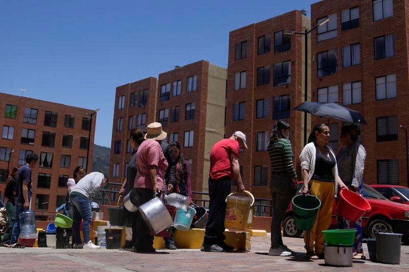 Residents line up to collect water from a truck during water rationing in La Calera, on the outskirts of Bogota, Colombia, Tuesday, April 16, 2024. Amid a drought linked to the El Niño weather pattern, several regions of Colombia have adopted measures to curb water consumption while reservoirs are low. (AP Photo/Fernando Vergara)